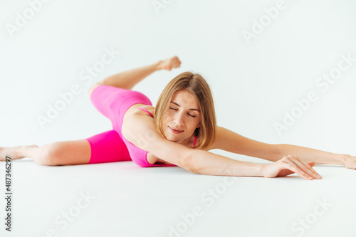 Positive lady is stretching on a white background, lying with a smile on his face and eyes closed and having fun