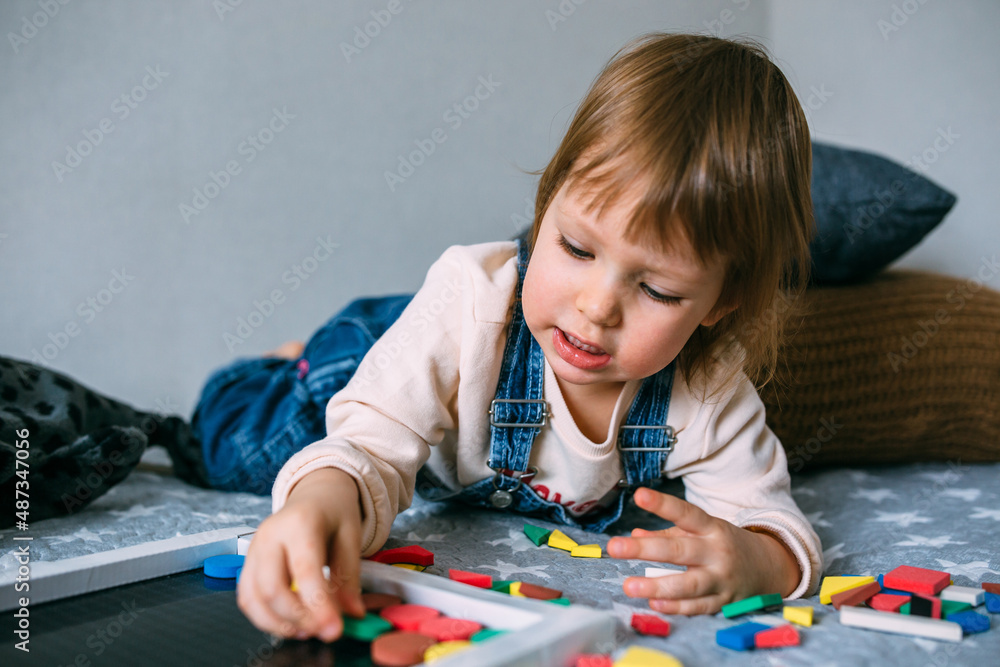 Child plays at home an educational game with a multi-colored magnetic puzzle Child plays at home an educational game with a multi-colored magnetic puzzle