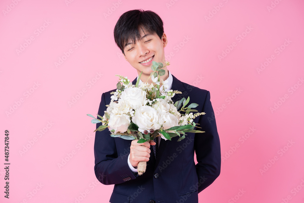 Young Asian groom posing on pink background Young Asian groom posing on pink background