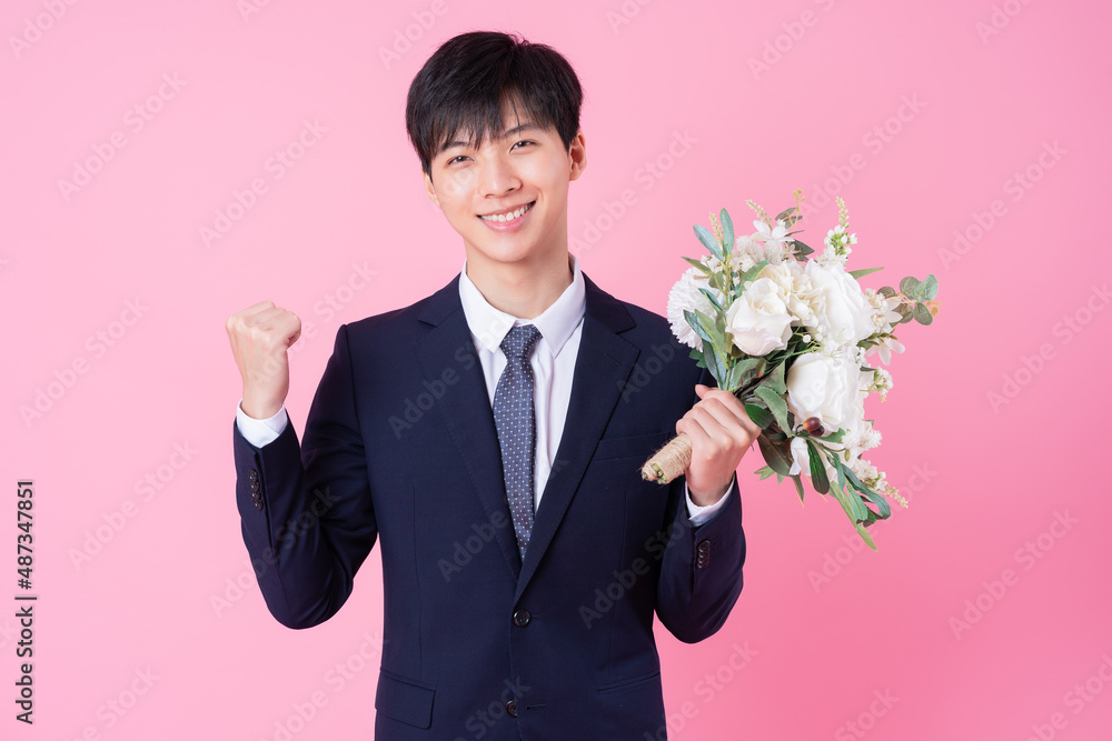 Young Asian groom posing on pink background Young Asian groom posing on pink background