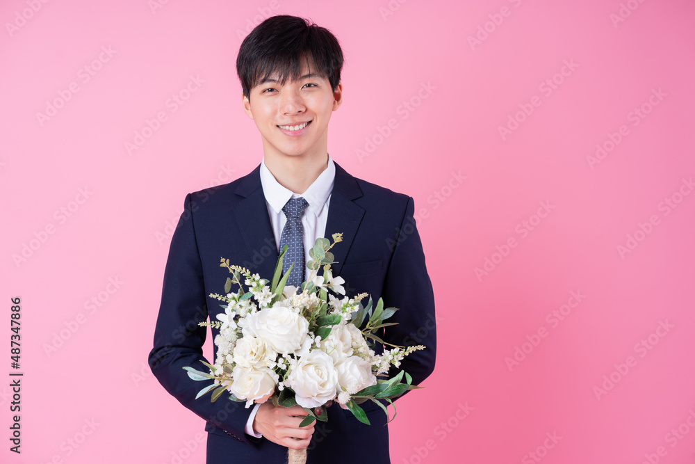 Young Asian groom posing on pink background Young Asian groom posing on pink background