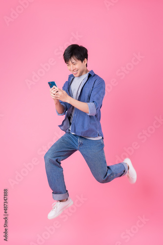 Fototapeta Young Asian man jumping on blue background