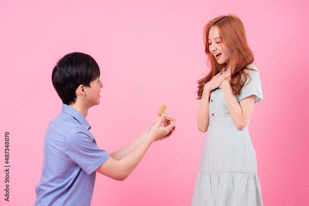 Young Asian man proposes to his girlfriend on a pink background Young Asian man proposes to his girlfriend on a pink background
