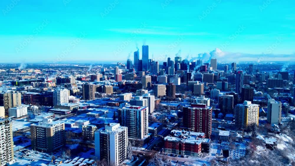 Edmonton Alberta winter sunny clear blue sky aerial hold overlooking residential buildings surrounding the downtown Capital City skyscrapers snow covered with steam pumping out of apartments offices Edmonton Alberta winter sunny clear blue sky aerial hold overlooking residential buildings surrounding the downtown Capital City skyscrapers snow covered with steam pumping out of apartments offices