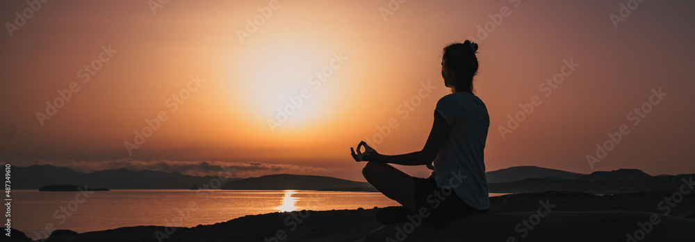 Fototapeta premium woman in white doing yoga and meditating by the sea