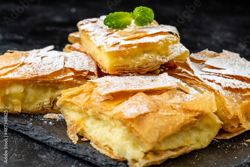 Greek bougatsa sliced on a dark table. Close-up.