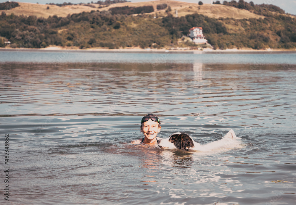 woman and dog swimming in lake