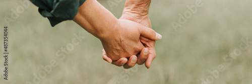happy senior couple holding hands. hands of man and woman hold each other. romance and love and support in elderly family. faceless husband and wife travel together in nature. countryside life. banner