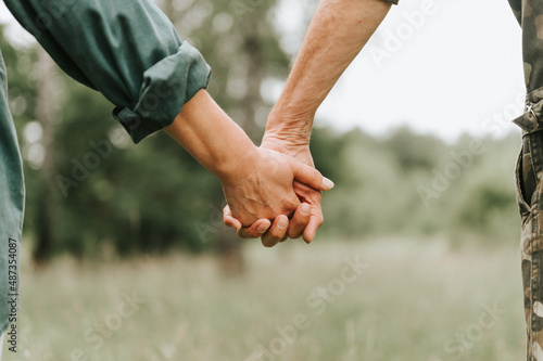 happy senior couple holding hands. hands of man and woman hold each other. romance and love and support in elderly family. faceless husband and wife travel together in nature. people countryside life