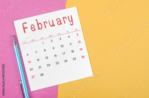 February 2022 calendar  with pen on multicolored background.