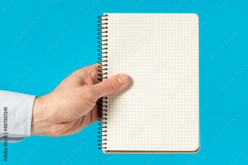Man hand holding a notebook with square grid Man hand holding a notebook with square grid