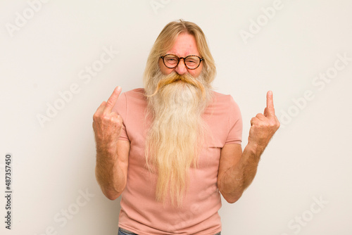 senior cool bearded man feeling provocative, aggressive and obscene, flipping the middle finger, with a rebellious attitude