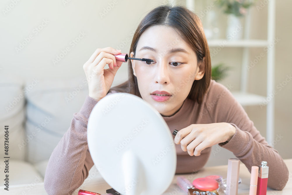 Beauty blogger concept, cute asian young woman, girl make up face by applying mascara brush on eyebrow, looking at the mirror at home. Female look with natural fashion style. Beauty blogger concept, cute asian young woman, girl make up face by applying mascara brush on eyebrow, looking at the mirror at home. Female look with natural fashion style.