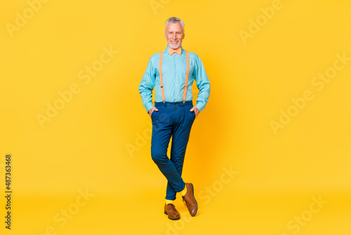 Photo of charming funky guy pensioner dressed teal shirt bowtie bow-tie walking isolated yellow color background