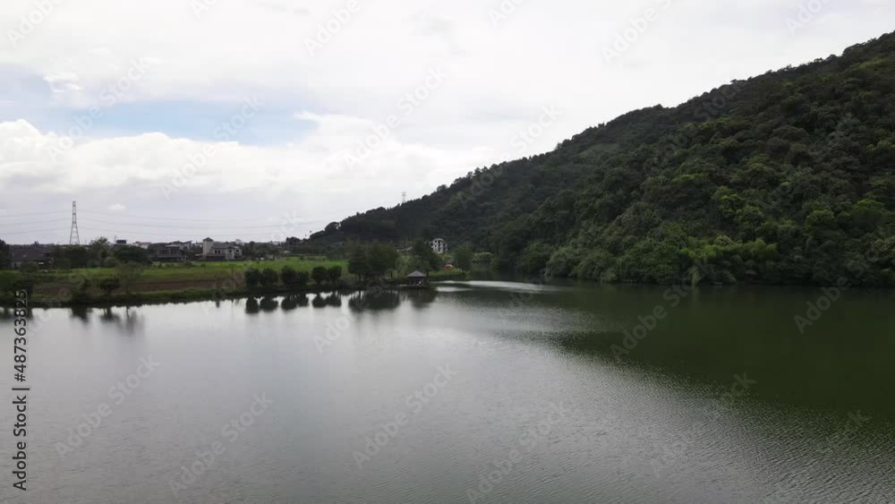 Green waters of lake reflecting trees and lush green mountain late in the afternoon Green waters of lake reflecting trees and lush green mountain late in the afternoon