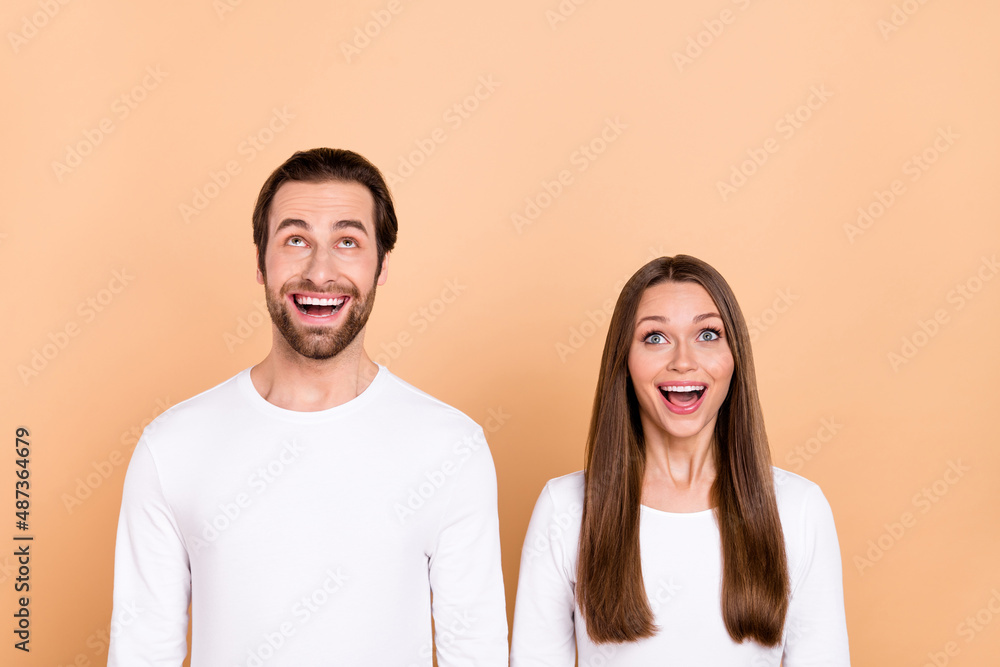Portrait of attractive cheerful amazed trendy brown-haired spouses look up copy space wow isolated over beige pastel color background Portrait of attractive cheerful amazed trendy brown-haired spouses look up copy space wow isolated over beige pastel color background