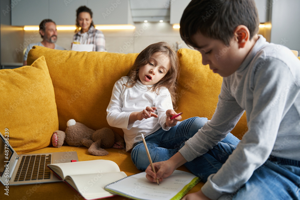 Boy writing homework exercise in notebook with sister Boy writing homework exercise in notebook with sister