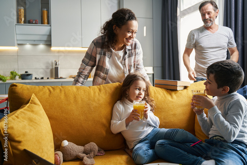 Kids drinking juice while mother smiling at them photo