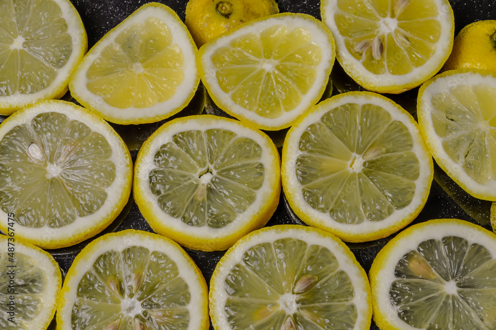 slices of organic Sicilian lemon arranged on a glittered black glass background slices of organic Sicilian lemon arranged on a glittered black glass background
