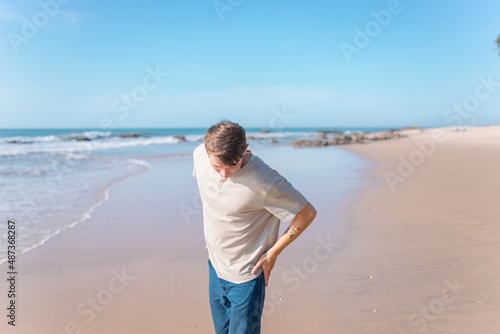 young caucasian man with full-arm tattoo in casual clothing walking on the beach © Aleksandr