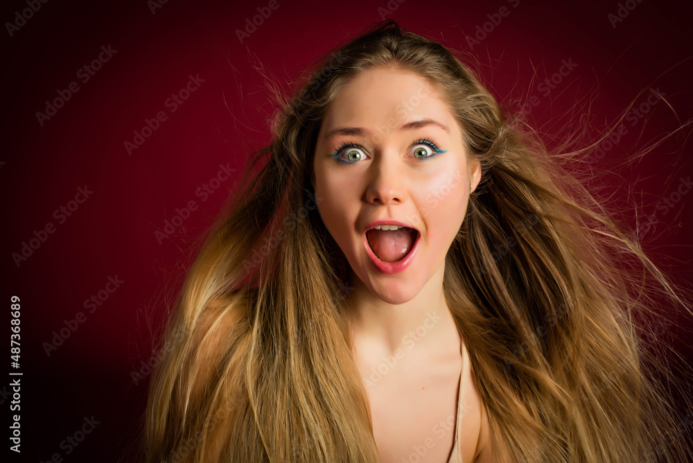 Image of excited screaming young woman standing on red background. Looking camera. Cute teenage student girl.