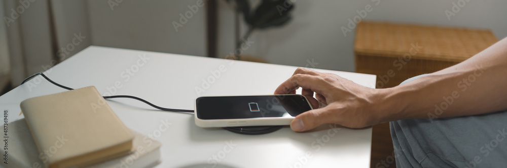 Man hands plugging a charger in a smart phone. Charging Smartphone with Wireless Charging Pad at Home Man hands plugging a charger in a smart phone. Charging Smartphone with Wireless Charging Pad at Home