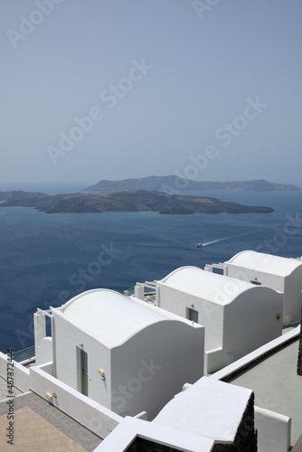View of luxury villas with balconies and a ferry boat next to the volcano of Santorini 