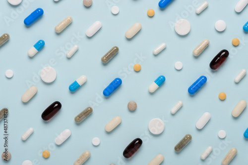 Pills pattern on blue background. Assorted medicine drugs texture flat lay.