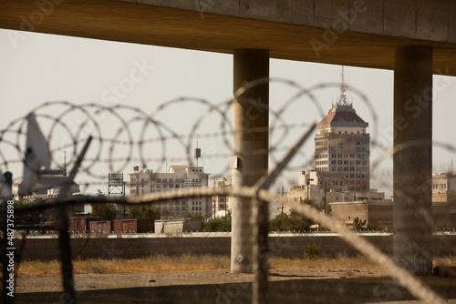 Barbed wire and a concrete overpass frame the downtown skyline of Fresno, California, USA.