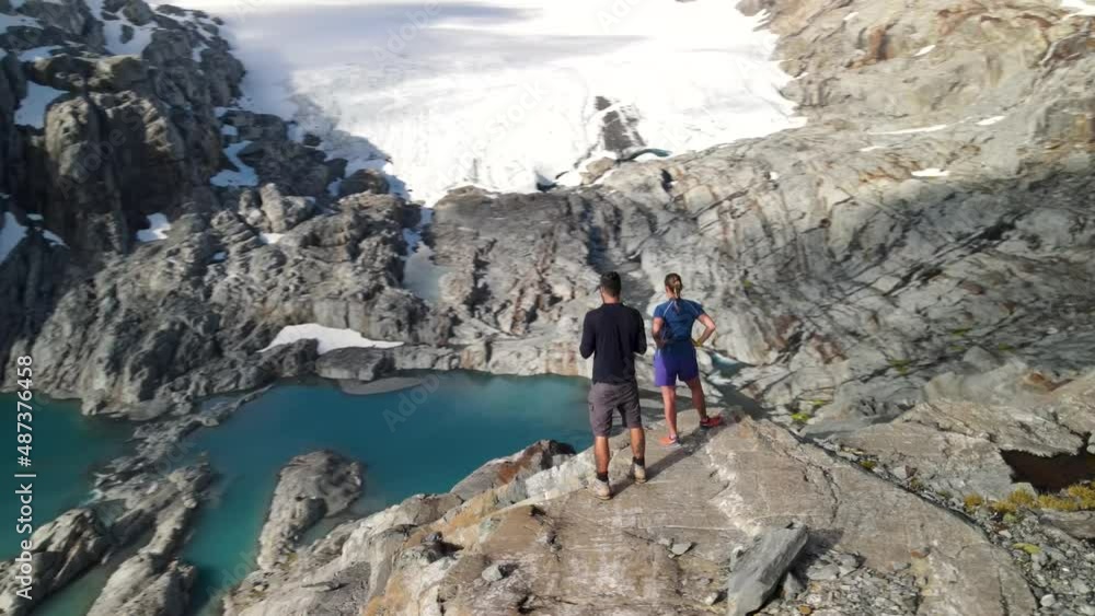 Couple young hikers enjoying breathtaking view of Mount Brewster Glacier, glacial lakes, rocky alpine terrain. New Zealand beautiful landscape. Couple young hikers enjoying breathtaking view of Mount Brewster Glacier, glacial lakes, rocky alpine terrain. New Zealand beautiful landscape.