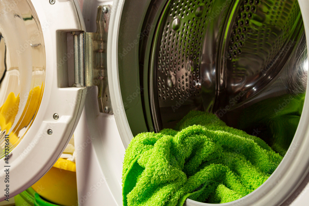 A modern washing machine with the door ajar and clothes inside. A modern washing machine with the door ajar and clothes inside.