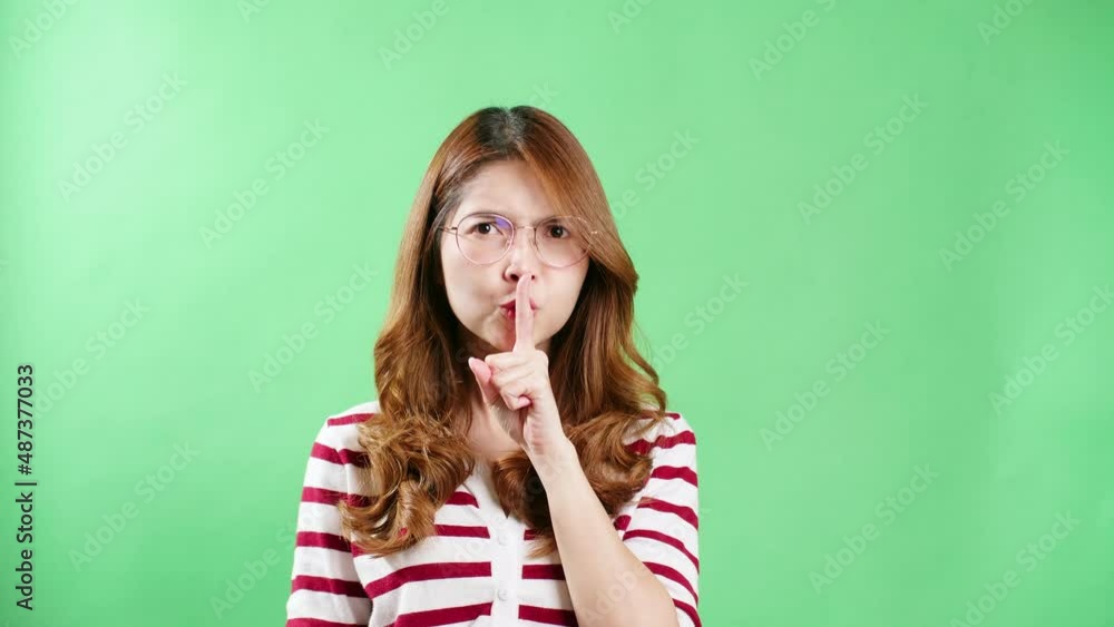 Young Asian woman with eyeglasses pointing to the eyes watching you gesture, keeping eyes on you, green screen background. Young Asian woman with eyeglasses pointing to the eyes watching you gesture, keeping eyes on you, green screen background.