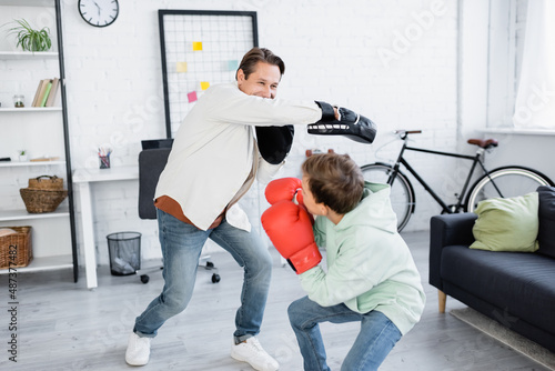 Dad and preteen son in boxing gloves training in living room © LIGHTFIELD STUDIOS