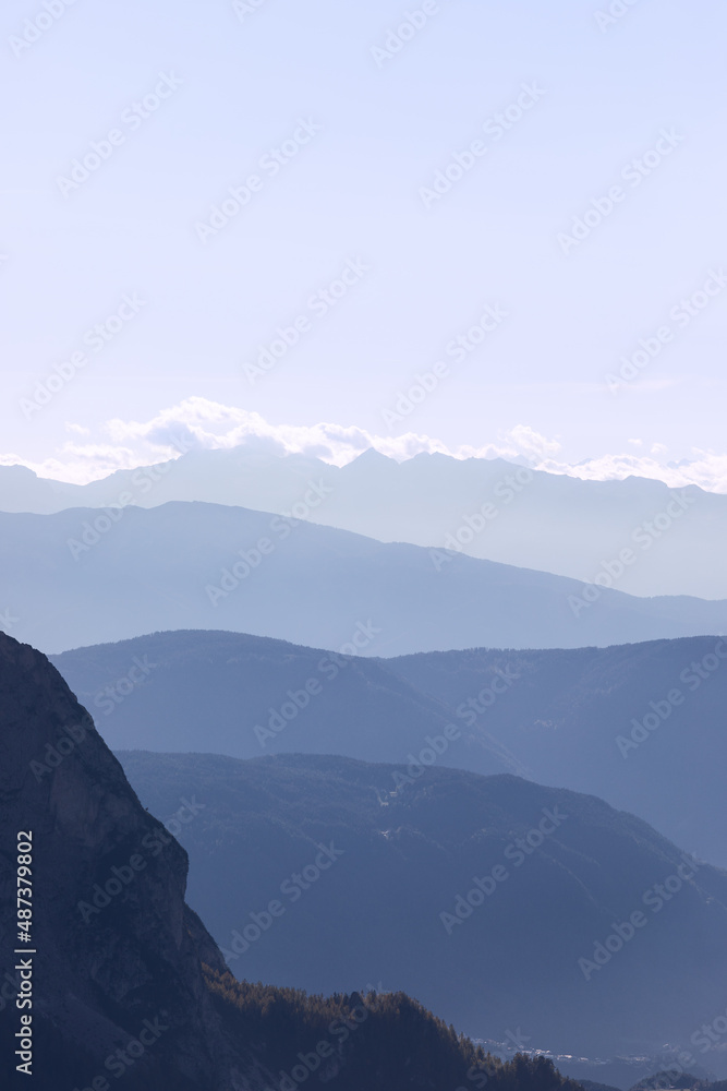 Mountain ranges of Val Gardena covered with morning haze in Seiser Alm, Italy (Vertical photo)