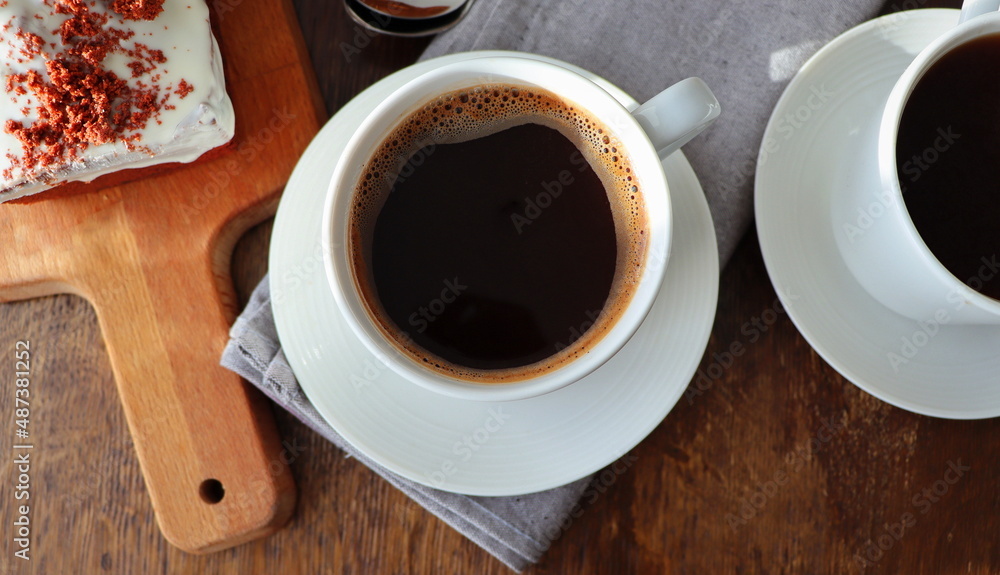 Red velvet cake and two coffee cups for breakfast on wooden background. Tasty dessert. Close up Red velvet cake and two coffee cups for breakfast on wooden background. Tasty dessert. Close up