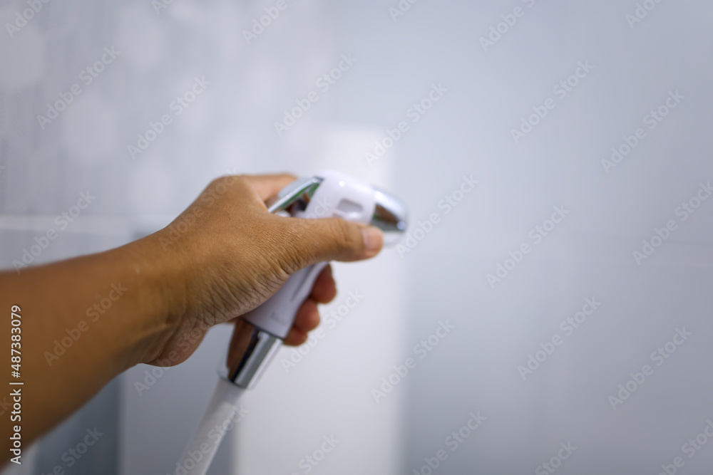 man holding a white bidet in the rest room after defecation