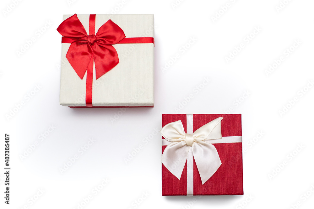 Two white and red gift boxes with ribbons and bows on a white background. Gifts for birthday or traditional holidays. Two gift boxes arranged diagonally with free space for text Two white and red gift boxes with ribbons and bows on a white background. Gifts for birthday or traditional holidays. Two gift boxes arranged diagonally with free space for text
