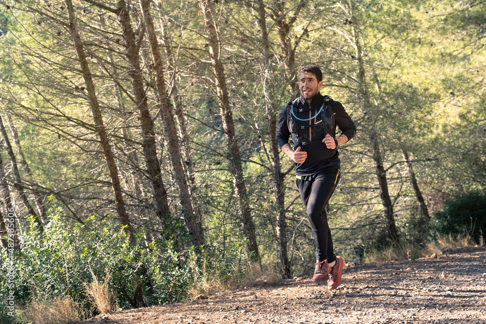 Fototapeta premium Man trail running in the mountains on a path.