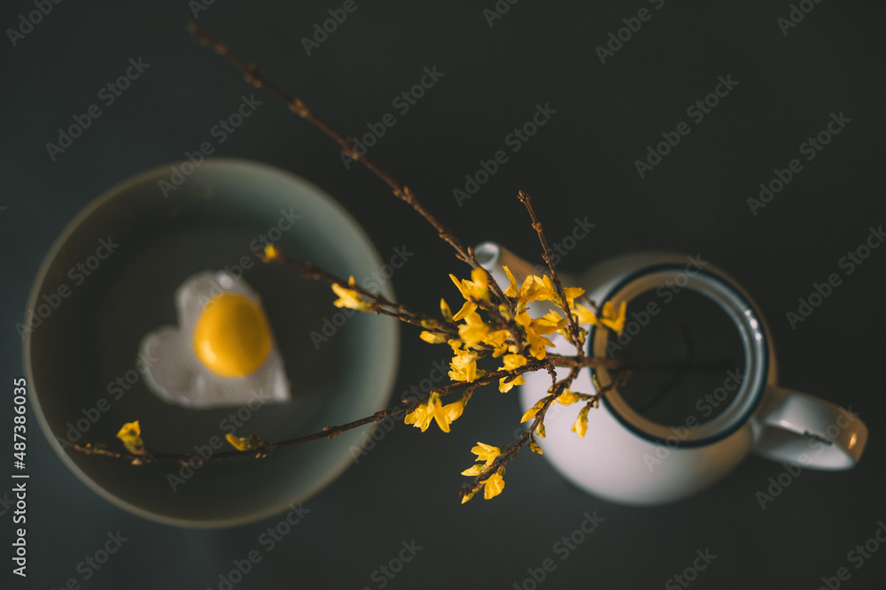 a branch with yellow forsythia flowers in a teapot