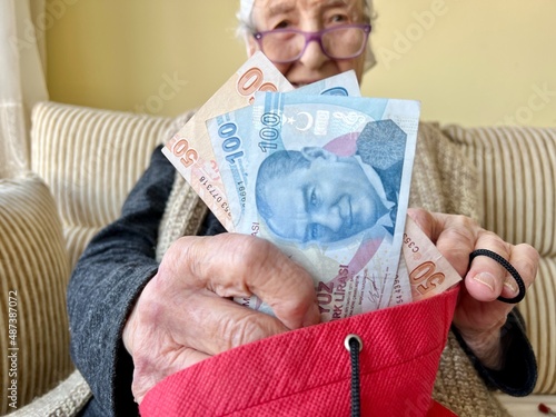 wrinkled hands of old woman holding some turkish lira banknotes photo