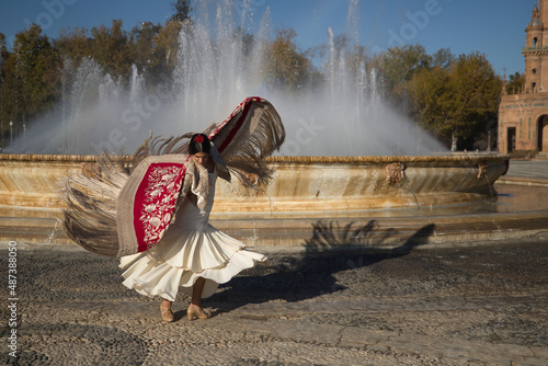 Fototapeta Young flamenco woman, Hispanic and brunette, with typical flamenco dance suit, dancing with red manila shawl with golden flowers