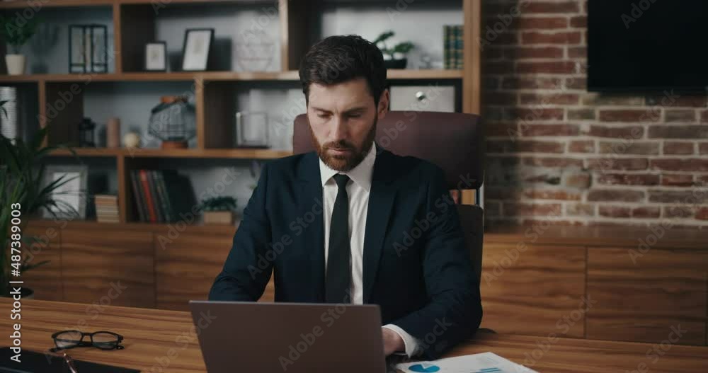 The trader checks the exchange rates. Man portrait in cinematographic light. Handsome businessman is working in the office The trader checks the exchange rates. Man portrait in cinematographic light. Handsome businessman is working in the office