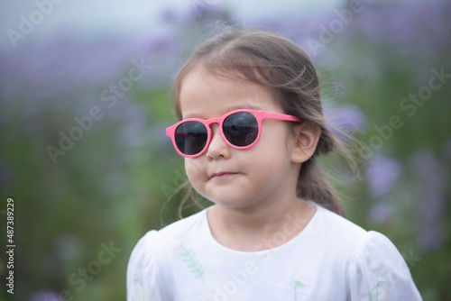 beautiful little girl wearing sunglasses in the field in summer