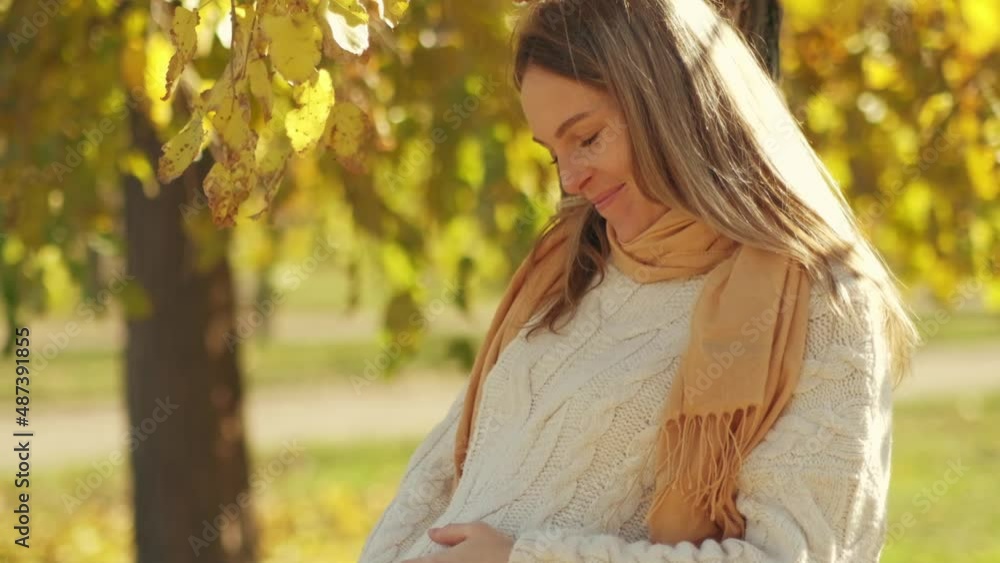 Attractive young pregnant woman with leaf holding her tummy in autumn park. Beautiful future mother having great time outside on sunny fall day and enjoying beautiful nature outdoors Attractive young pregnant woman with leaf holding her tummy in autumn park. Beautiful future mother having great time outside on sunny fall day and enjoying beautiful nature outdoors
