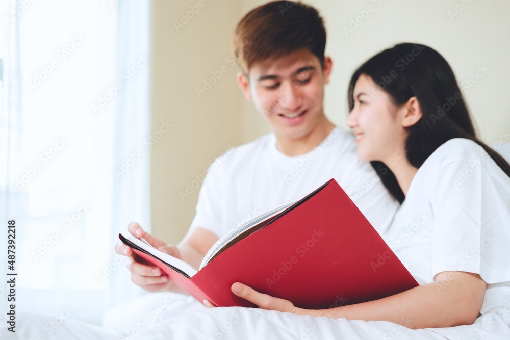 asian couples planning for future looking books, buying life insurance, buying houses, looking at wedding photos.