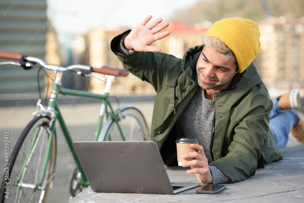 Hispanic man making video conference outdoors beside his bicycle