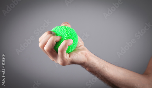 Male hand holding green stress ball.