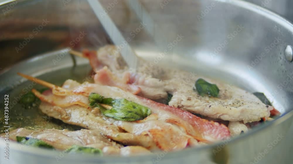 Person frying saltimbocca on wooden sticks on pan Person frying saltimbocca on wooden sticks on pan