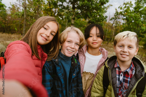 Multiracial four teenagers taking selfie during hiking in forest