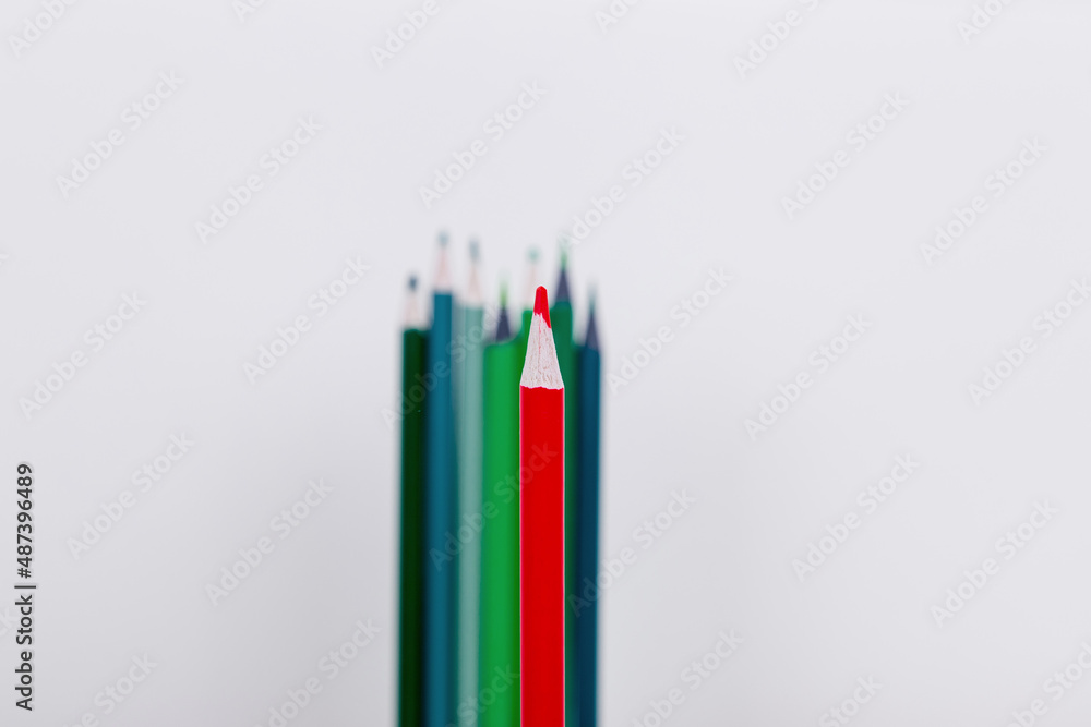 a red pencil in the foreground as a leader. a few pencils in the background like a crowd. wooden colored pencils on a white background a red pencil in the foreground as a leader. a few pencils in the background like a crowd. wooden colored pencils on a white background